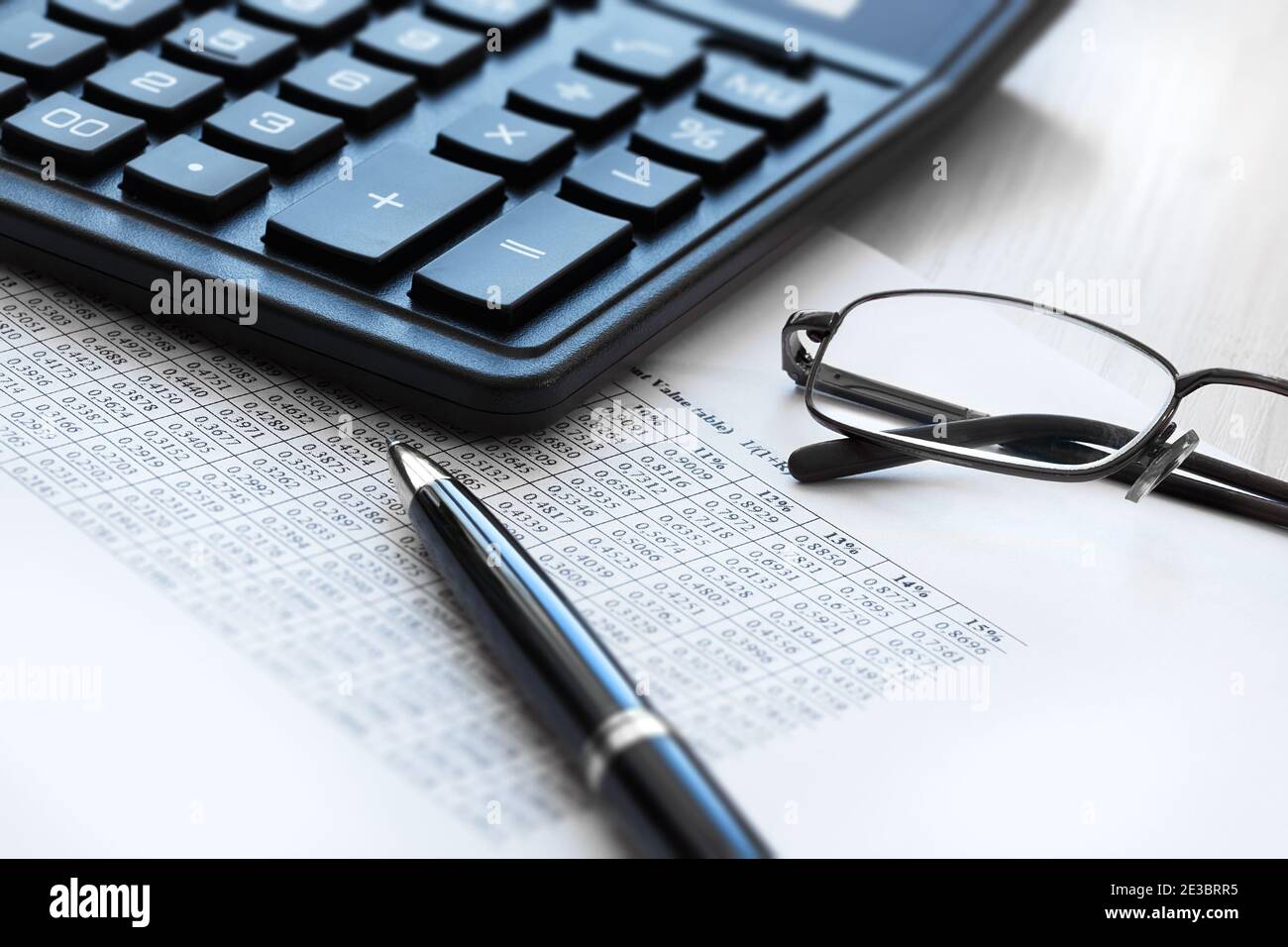 La vita still di affari di una calcolatrice, degli occhiali, della penna a sfera e di una tabella con i numeri. Il concetto di rendicontazione, contabilità. Foto Stock