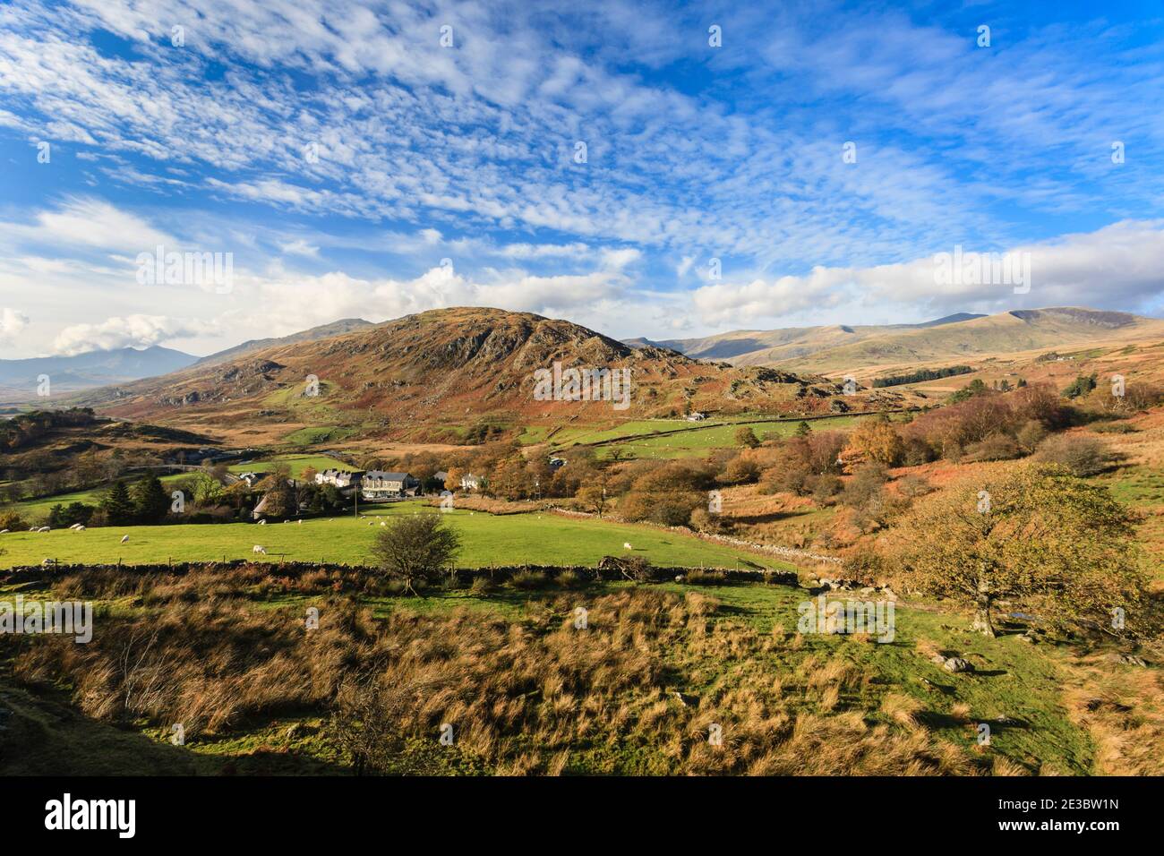 Vista sopra il villaggio a Cefn y Capel e lontane montagne nel Parco Nazionale di Snowdonia in autunno. Capel Curig, Conwy, Galles del Nord, Regno Unito, Gran Bretagna Foto Stock