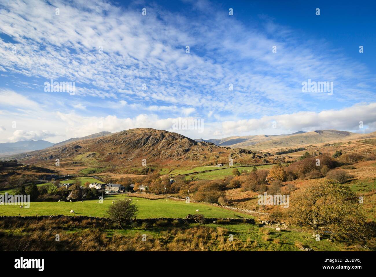 Vista sopra il villaggio a Cefn y Capel e lontane montagne nel Parco Nazionale di Snowdonia in autunno. Capel Curig, Conwy, Galles del Nord, Regno Unito, Gran Bretagna Foto Stock
