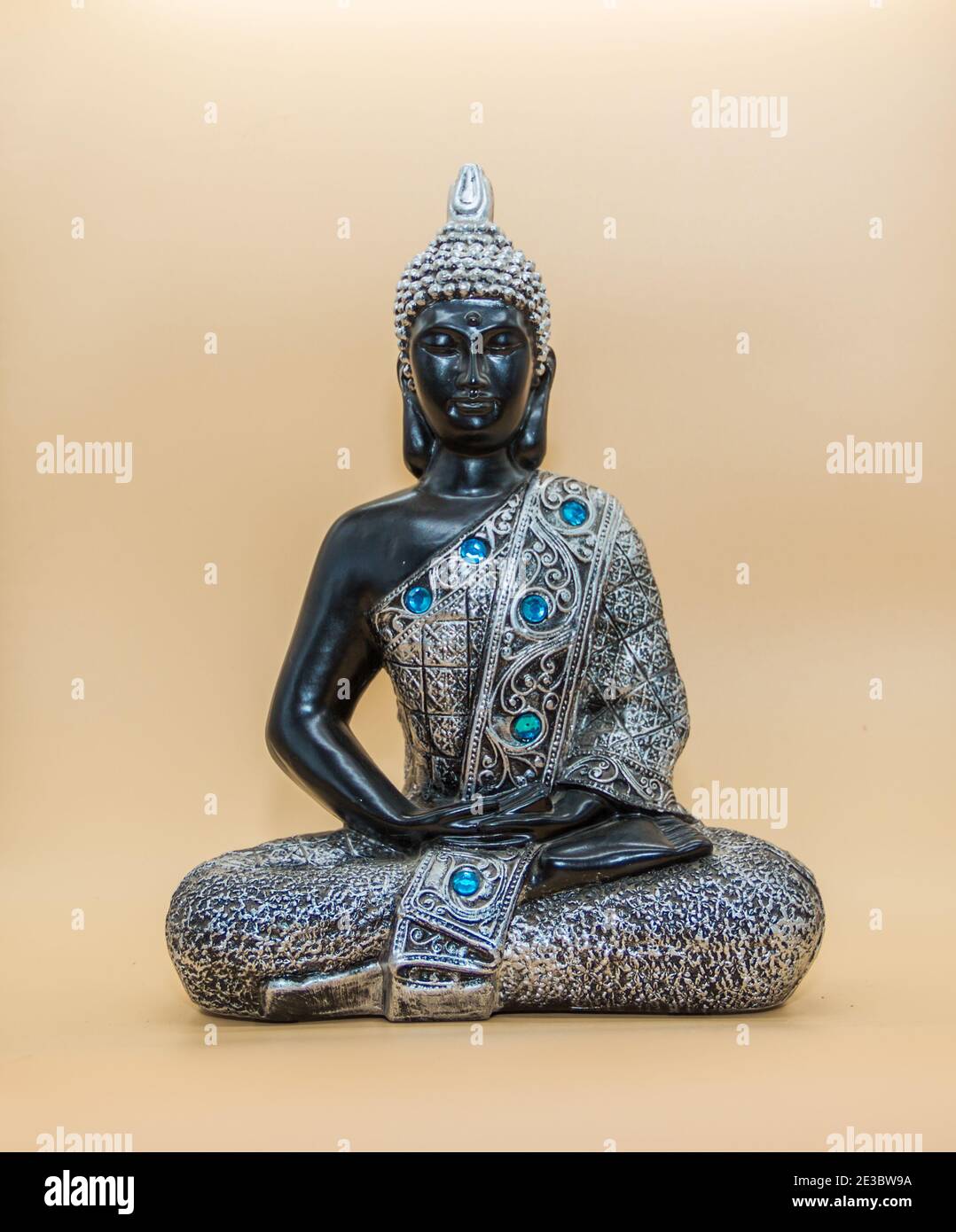 una piccola immagine di buddha in posizione di loto isolato sopra sfondo chiaro Foto Stock
