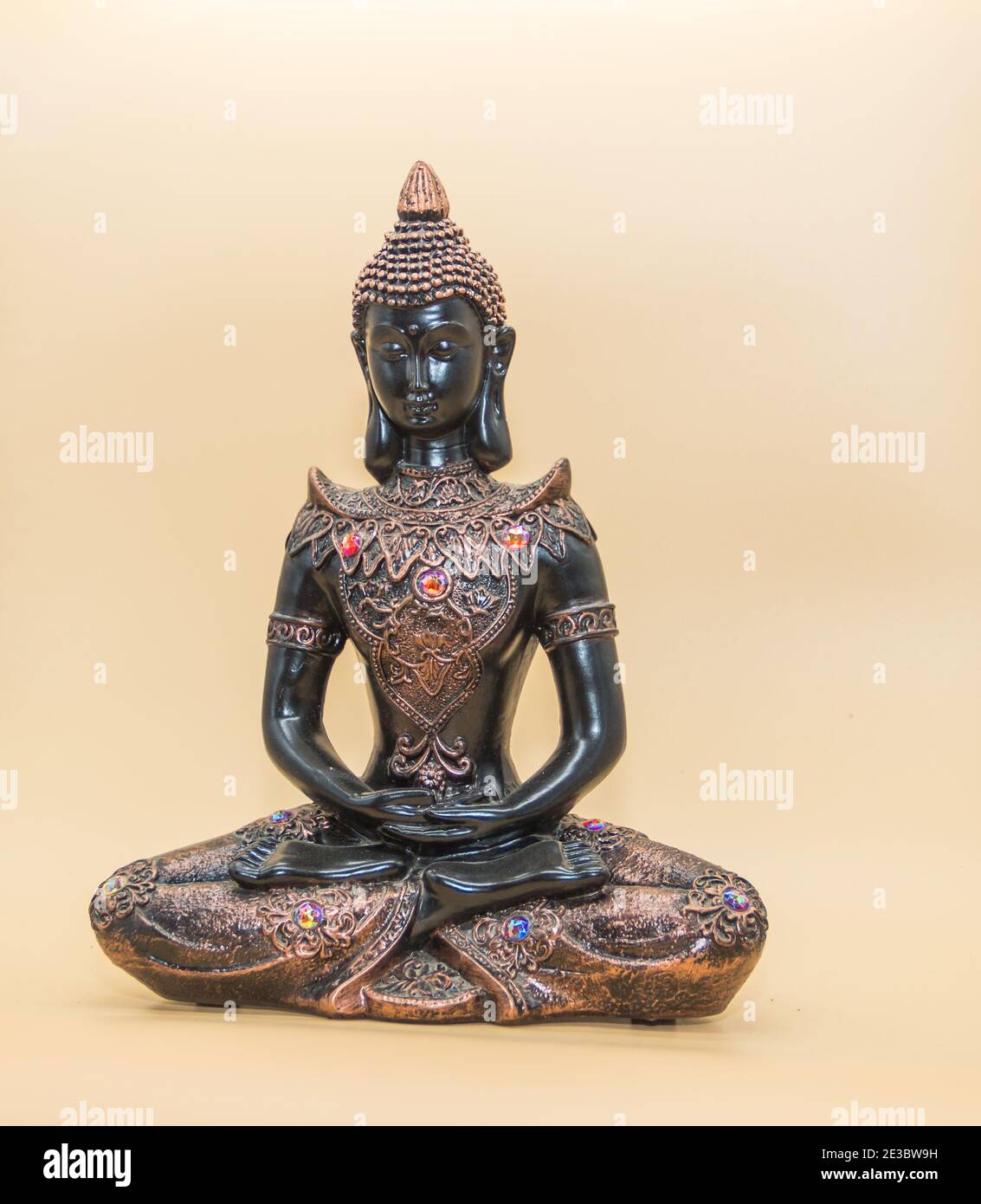una piccola immagine di buddha in posizione di loto isolato sopra sfondo chiaro Foto Stock