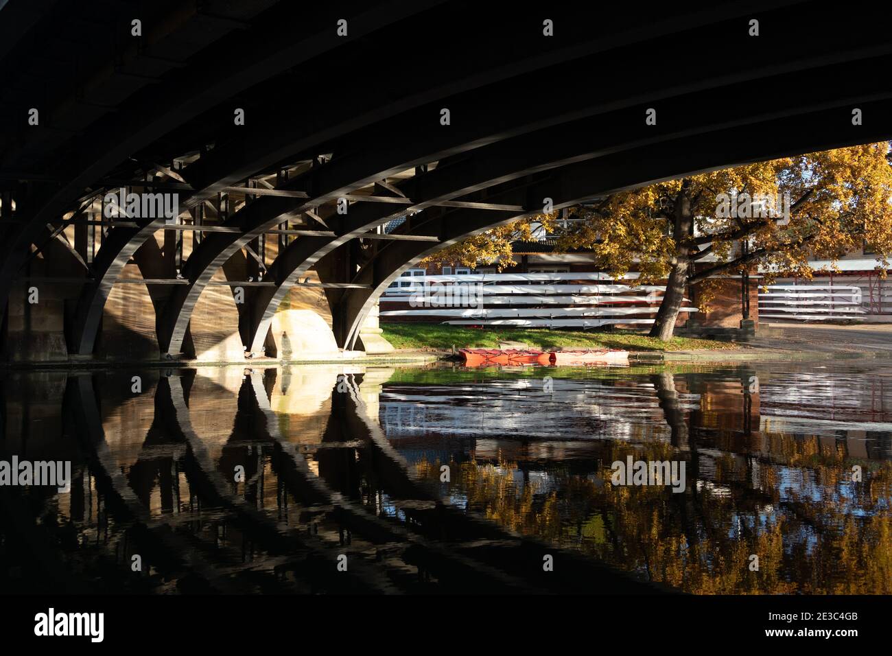 Sotto il ponte Victoria con riflessi sul fiume e canottaggio Barche sulla riva del fiume sullo sfondo River Cam Cambridge, Inghilterra Foto Stock