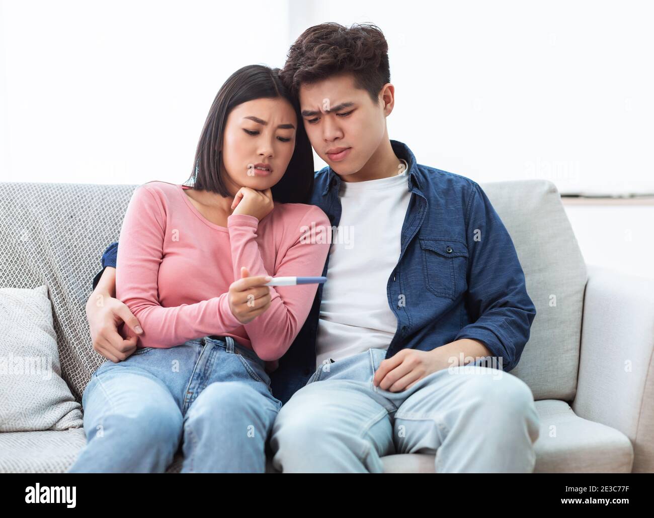 Frustrata coppia asiatica Holding negative Pregnancy Test seduta a casa Foto Stock