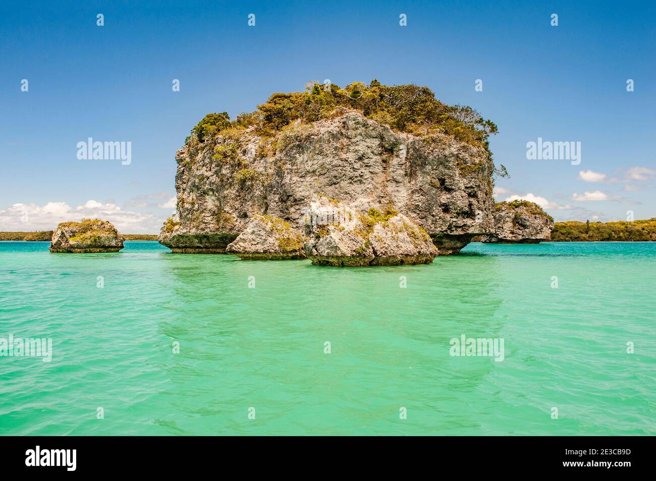 Un'isola rocciosa delle acque turchesi della Baie d'UPI all'Île des Pins, Nuova Caledonia Foto Stock