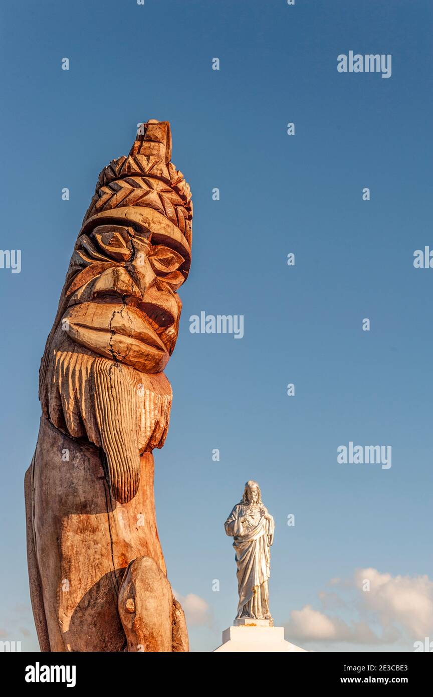 Pali totem scolpiti che proteggono una statua di un santo cattolico, St Maurice Bay, vicino a Vao, Ile des Pins, Nuova Caledonia Foto Stock