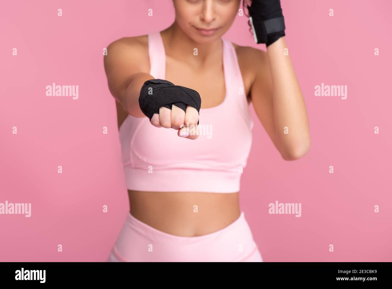 vista tagliata di giovane donna in abbigliamento sportivo con schiavitù sopra lotta mani isolato su rosa Foto Stock