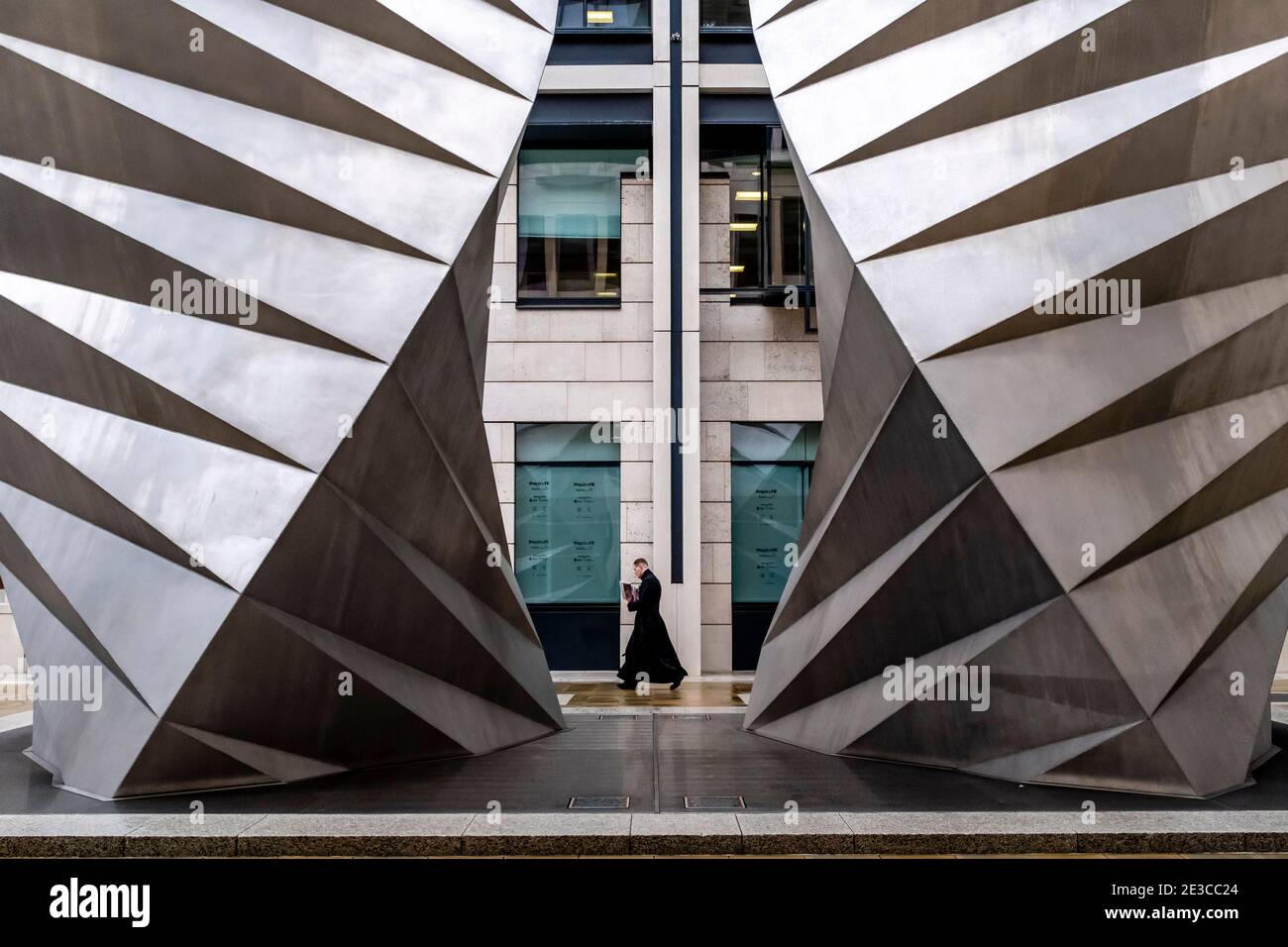 Un uomo che indossa un cassock Passeggiate oltre le tende Paternoster, Londra, Regno Unito. Foto Stock