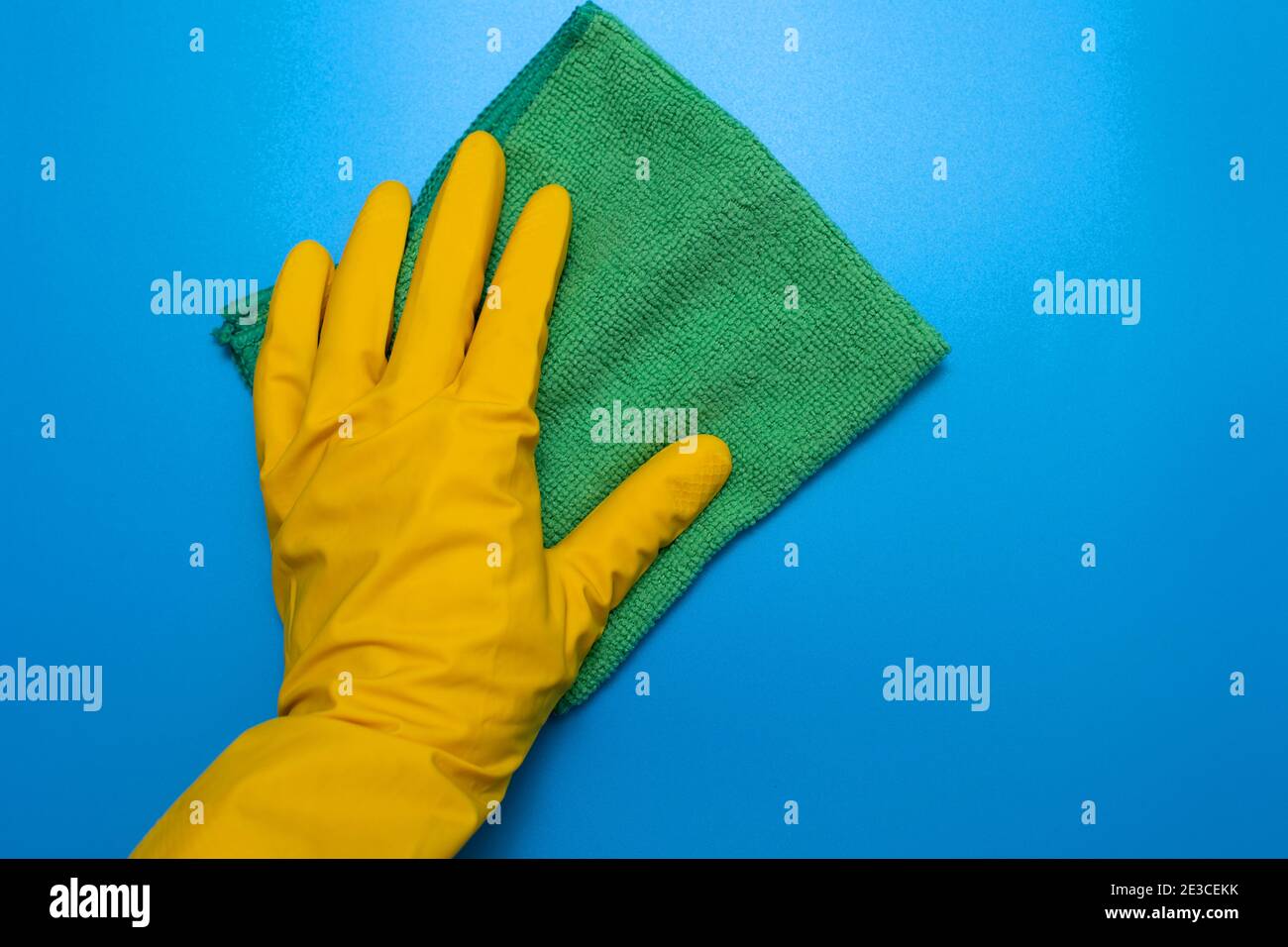 Guanto giallo con straccio verde di panni in microfibra su blu sfondo Foto Stock
