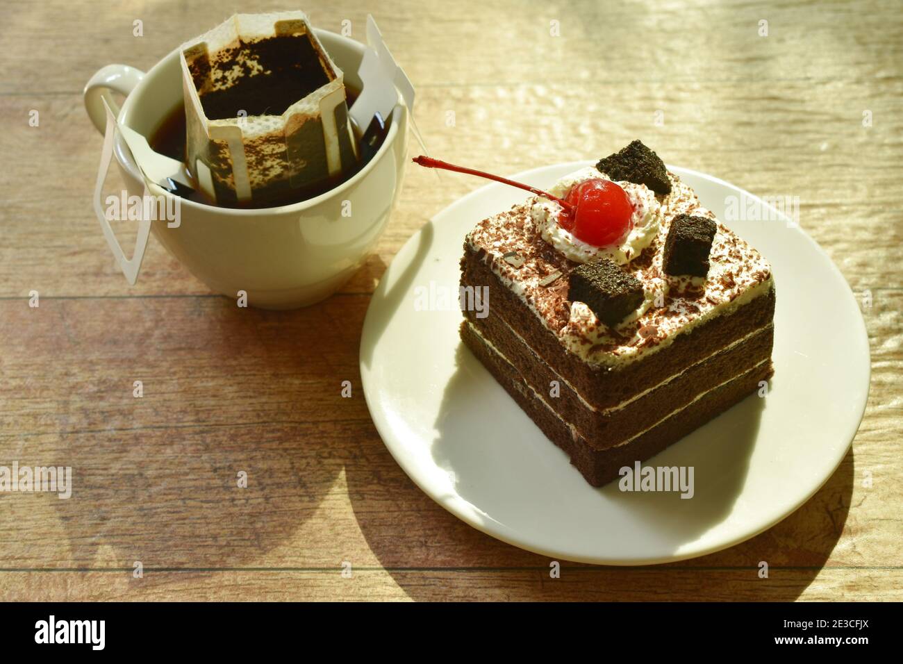 torta nera più piccante con crema di ciliegia e caffè caldo filtro antigoccia nel bicchiere Foto Stock
