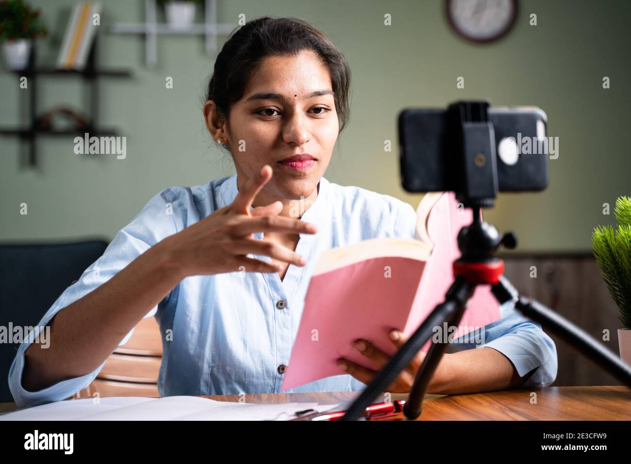 Giovane ragazza occupato a parlare con gli studenti sul telefono cellulare durante classe virtuale online a casa durante la covid-19 o la pandemia del coronavirus - concetto di e-teach Foto Stock