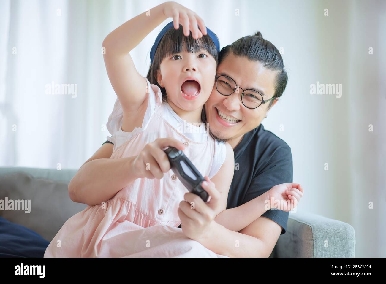 Asian Padre e cute figlia godere e giocare gioco di console in vacanza a casa Foto Stock