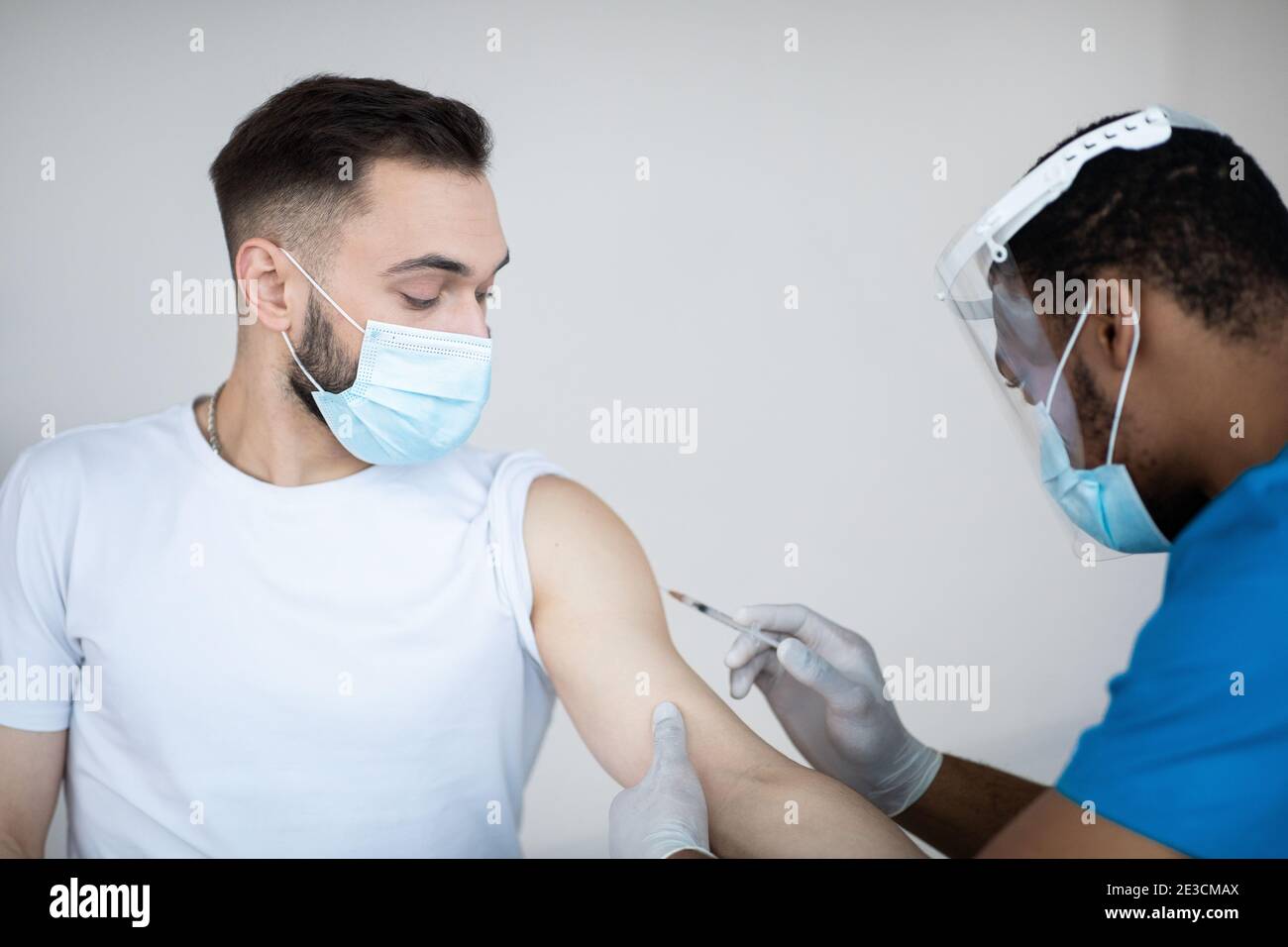 Giovane uomo caucasico che riceve iniezione di vaccino del coronavirus in ospedale. Sanità e prevenzione globale delle infezioni Foto Stock
