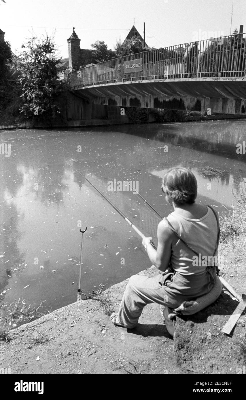 30 luglio 1984, Sassonia, Brinnis: Un pescatore si siede nell'estate 1984 al Wallgraben di Delitzsch al Schillerbrücke con la sua canna da pesca. Data esatta della registrazione non nota. Foto: Volkmar Heinz/dpa-Zentralbild/ZB Foto Stock