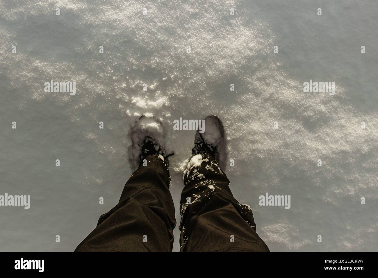 Dettaglio di stivali caldi e impermeabili in neve fresca profonda.piedi femminili in scarpe nere, passeggiata invernale in neve.Vista ad alto angolo delle gambe femminili in piedi Foto Stock