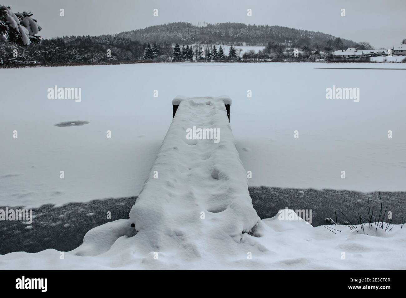 Molo in legno sul lago coperto di neve fresca. Inverno stagno innevato con piccolo molo. Lago foggy con colline. Bianco inverno countryside.Christmas idilliaco Foto Stock