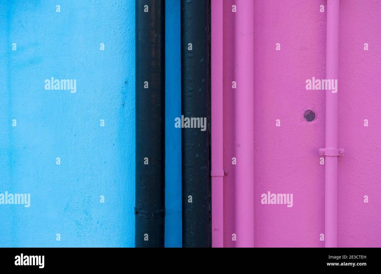 Pareti blu e rosa con tubi panati negli stessi colori e tubi neri Foto Stock