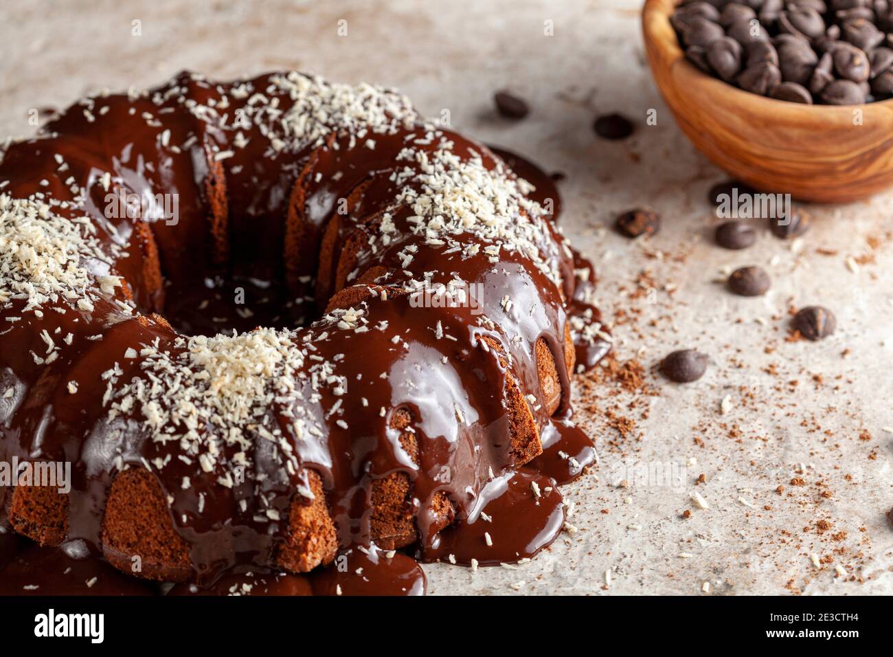 Torta al cioccolato con glassa fusa e gocce di cioccolato in una ciotola sullo sfondo. La decorazione di questa deliziosa torta è stata completata con spr Foto Stock