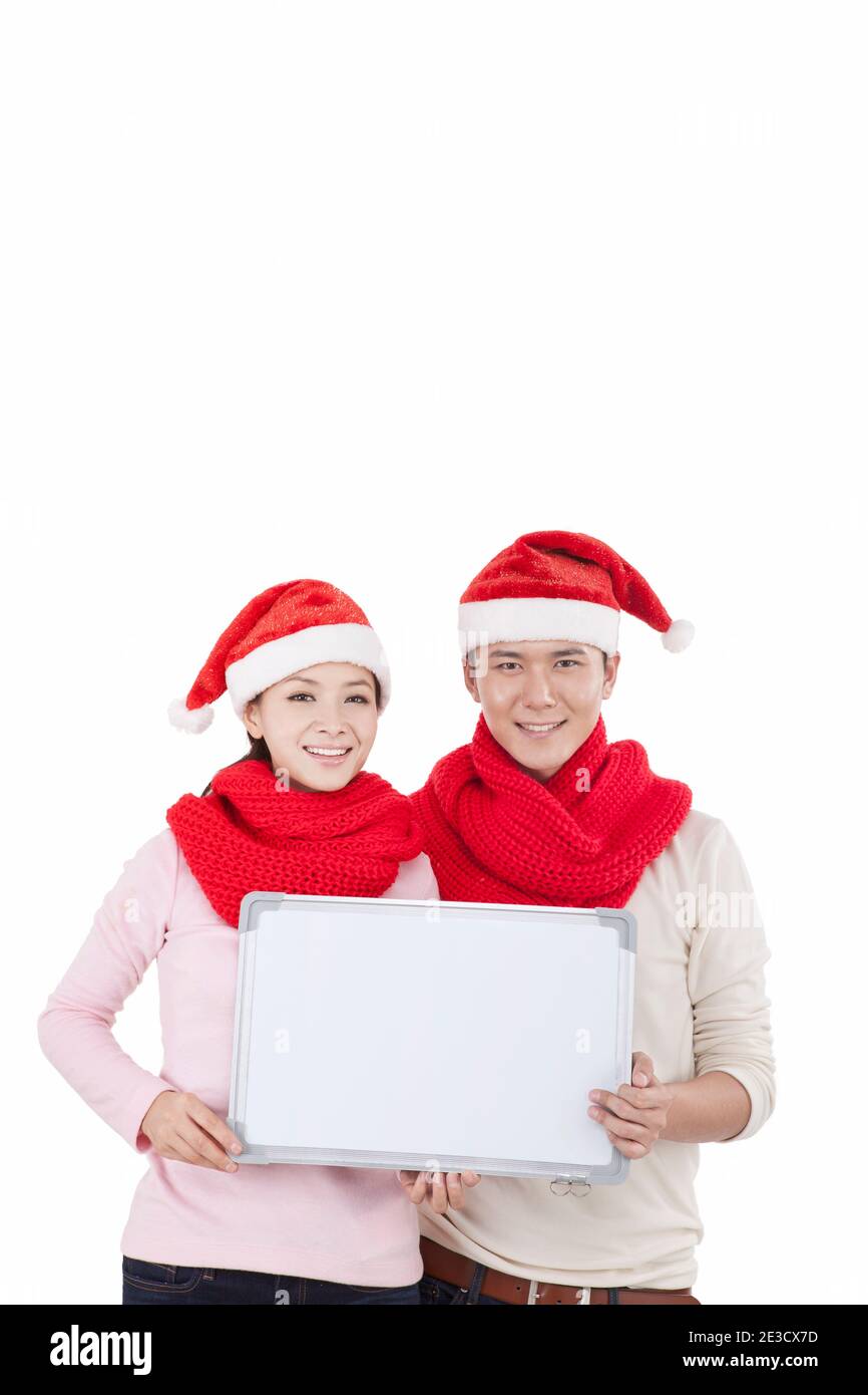 Ritratto di giovane coppia che indossa cappelli Santa, tenuta lavagna alta qualità foto Foto Stock