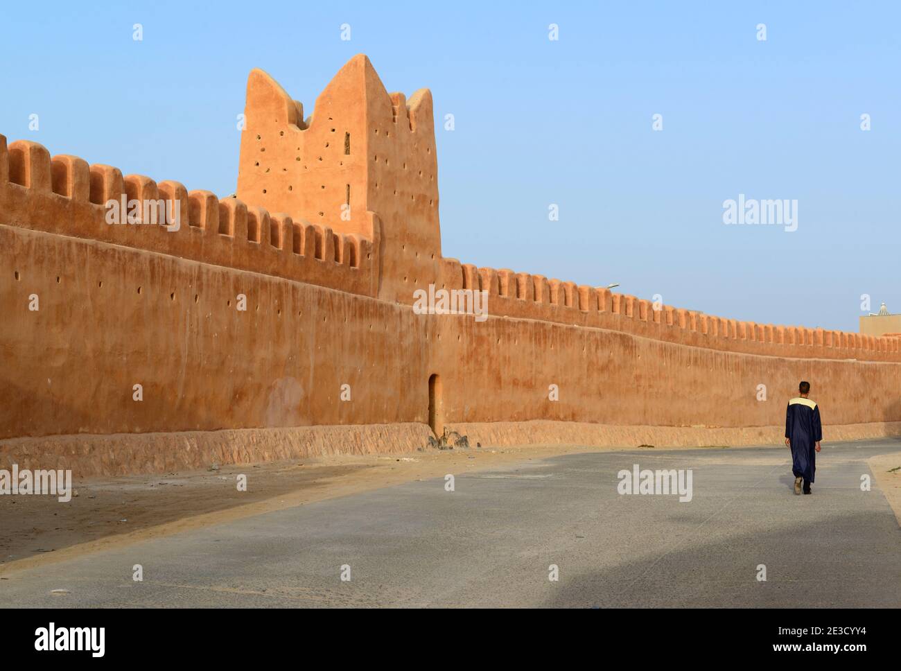 Uomo che cammina lungo le mura della città vecchia di Tiznit, Marocco. Foto Stock