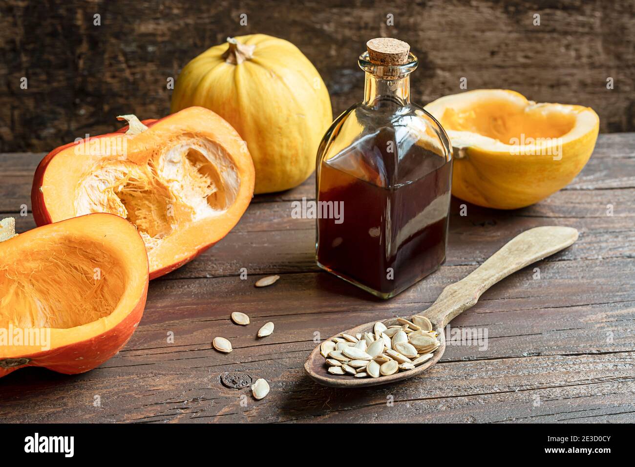 Zucche e una bottiglia con semi di zucca organici e deliziosi olio su un vecchio tavolo di legno scuro Foto Stock