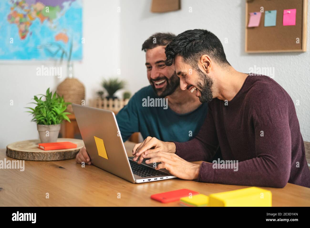 Gli uomini gay usano un computer portatile in soggiorno a casa - l'amore omosessuale e l'uguaglianza di genere nel concetto di relazione Foto Stock