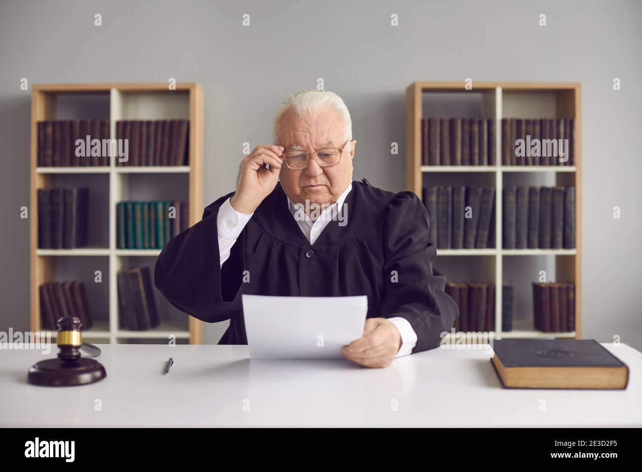 L'uomo anziano professionista giudica i dettagli di apprendimento del caso su carta durante la corte Foto Stock