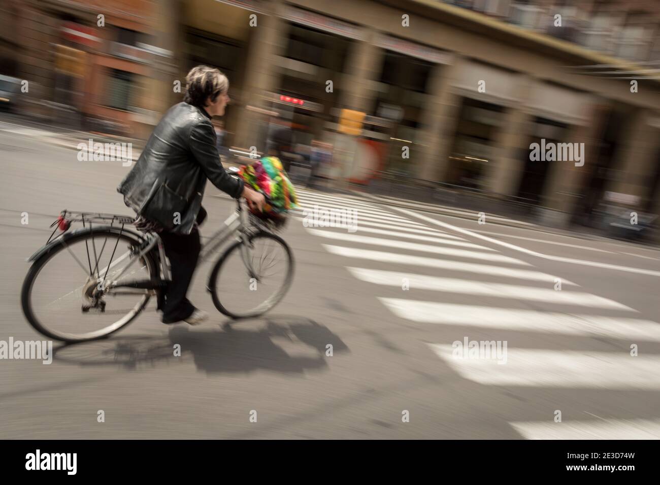 Una persona in bicicletta con sfocatura del movimento viaggia verso il basso Una strada a Bologna Italia Foto Stock