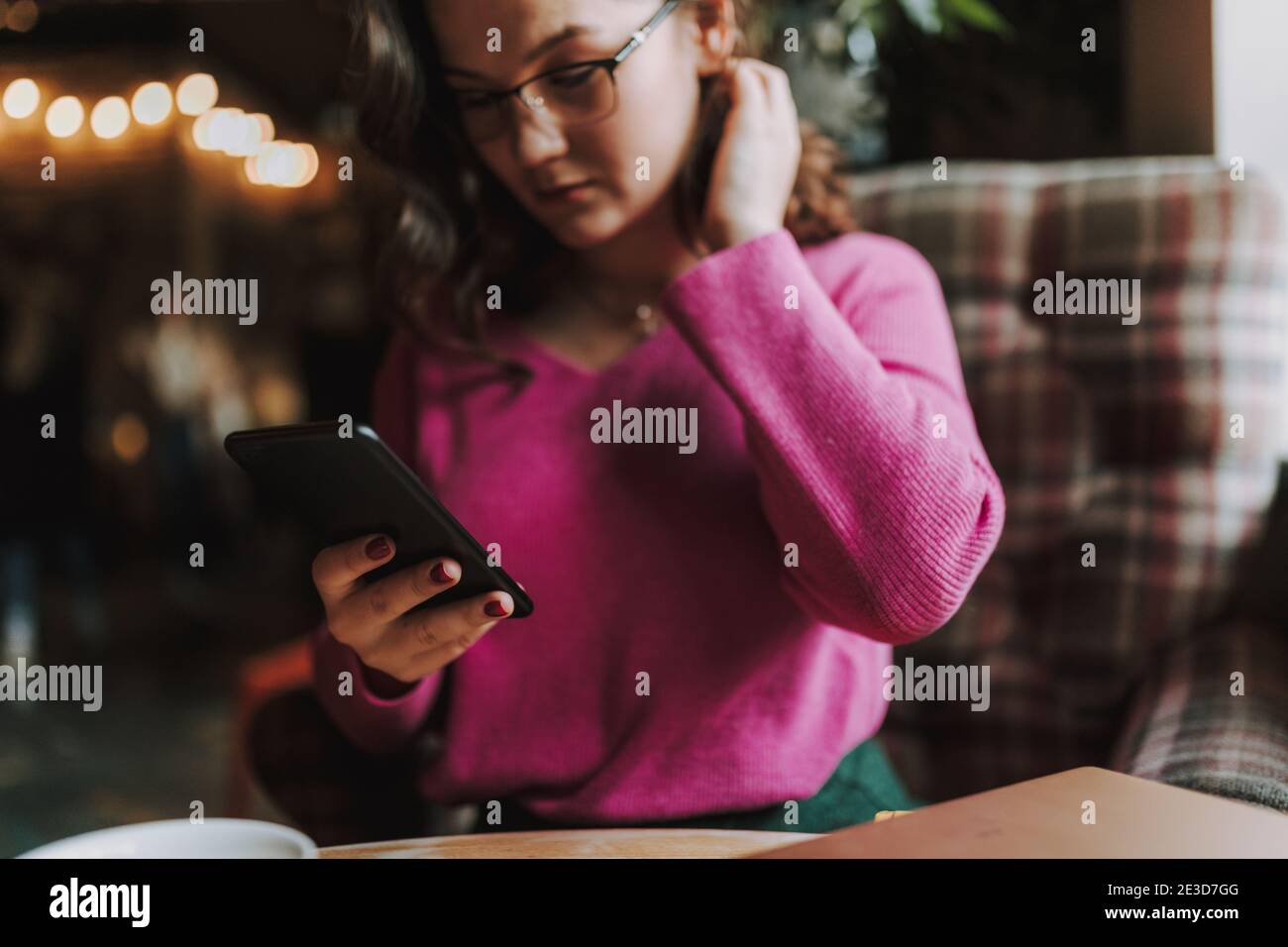 Foto ritagliata di bella signora seduta in caffetteria e. digitazione sullo smartphone Foto Stock