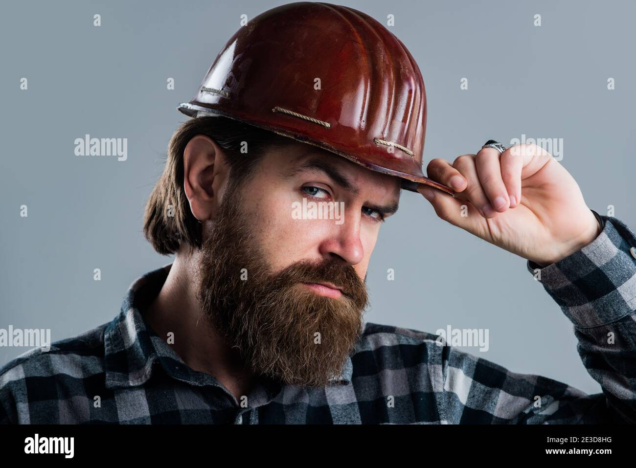 Si gode la barba perfetta. Costruire e riparare. Bel lavoratore. Lavoratore maschile in uniforme. ragazzo costruttore con strumento di lavoro. Brutale hipper maturo indossare camicia a scacchi e cappello. Giorno del lavoro. Foto Stock
