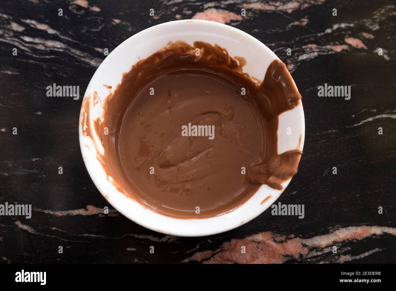 Il cioccolato caldo è stato fuso in un recipiente di plastica bianco. Primo piano. Foto Stock
