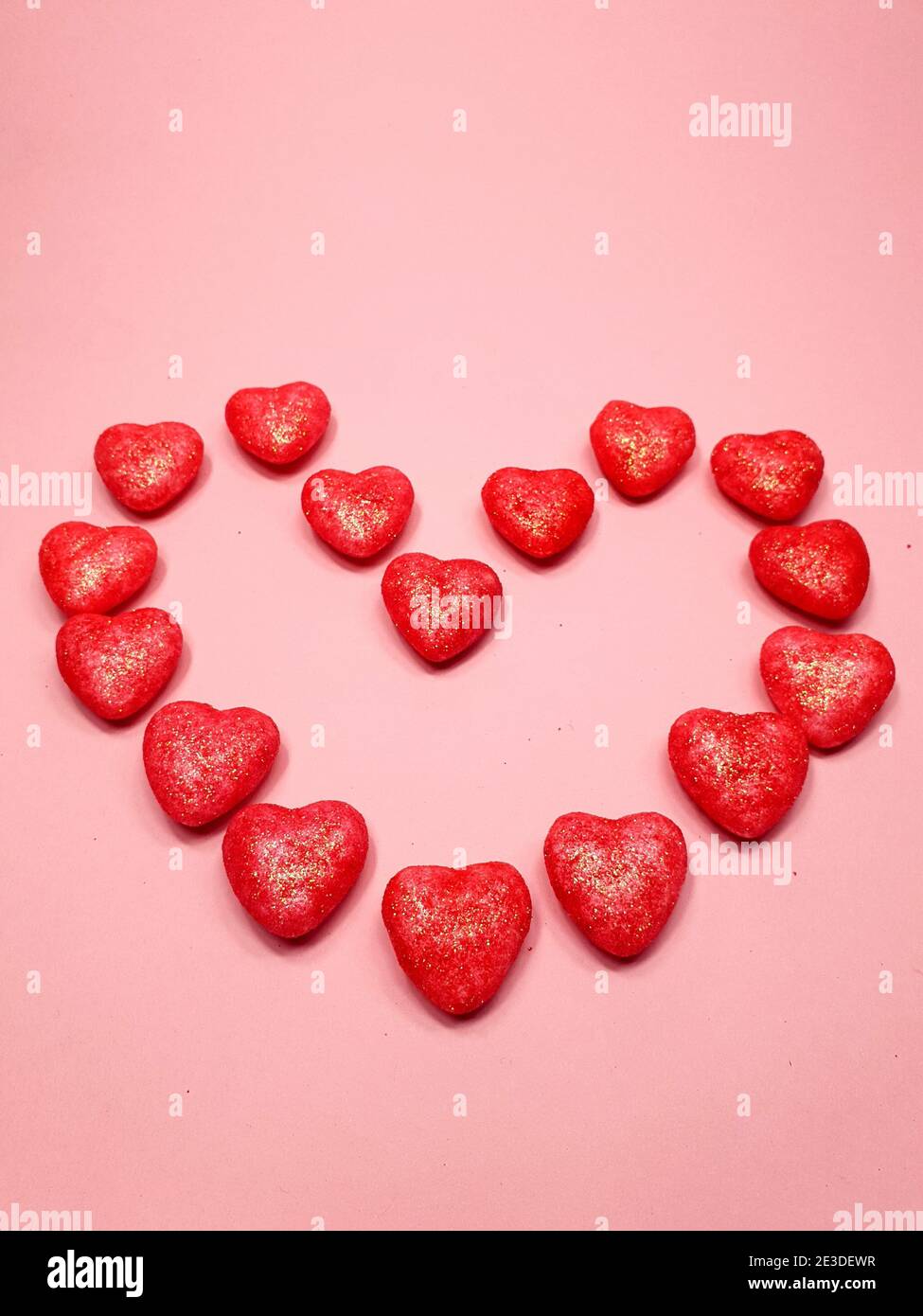 un grande cuore di piccoli cuori rossi su uno sfondo di colore rosa tenue, spazio di copia. Concetto di San Valentino per il design Foto Stock