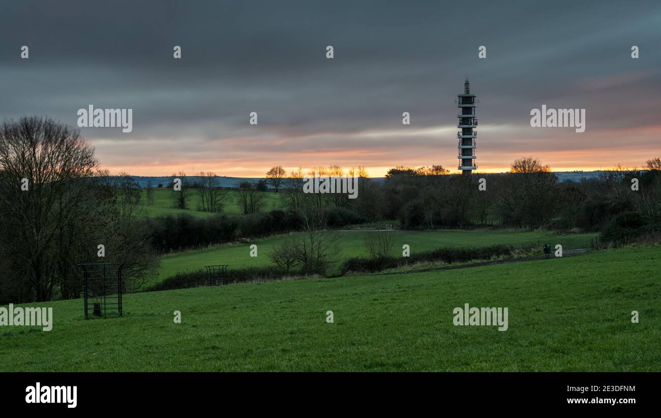 Il sole tramonta dietro la torre del trasmettitore Purdown BT a Stoke Park, Bristol. Foto Stock