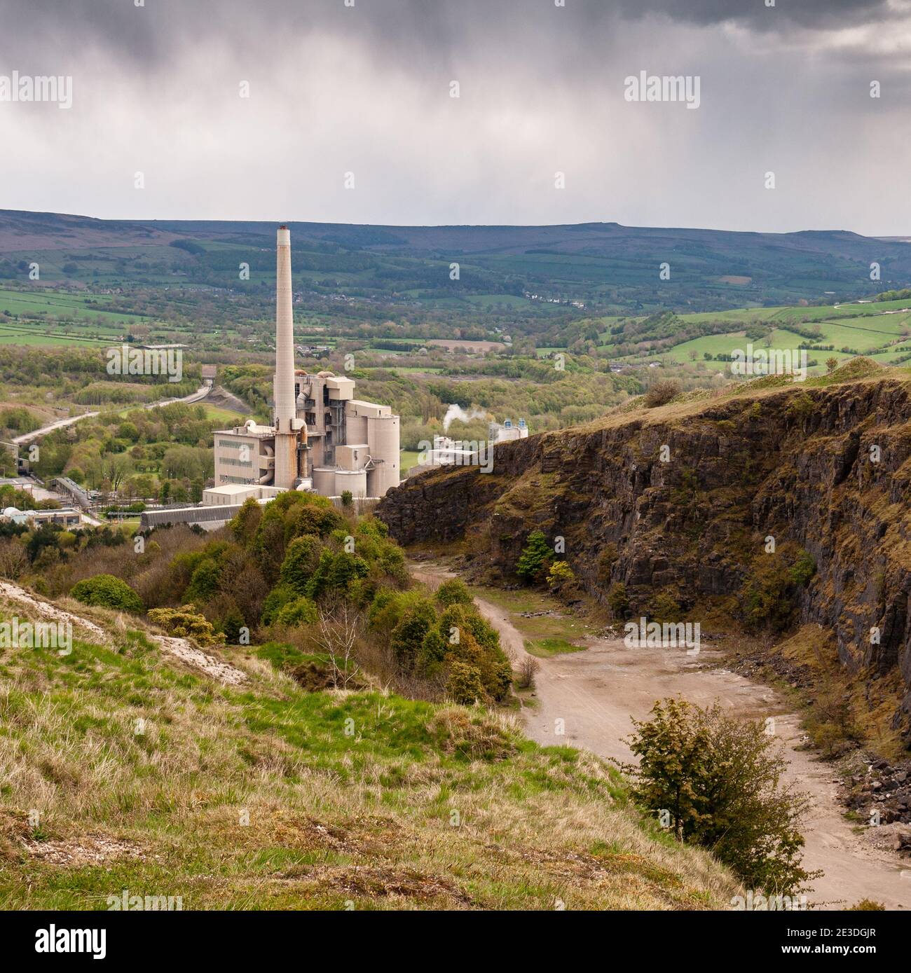 Una cava di pietra calcarea e una fabbrica industriale di cemento dominano la vista della Hope Valley e delle brughiere del Peak District in Inghilterra. Foto Stock