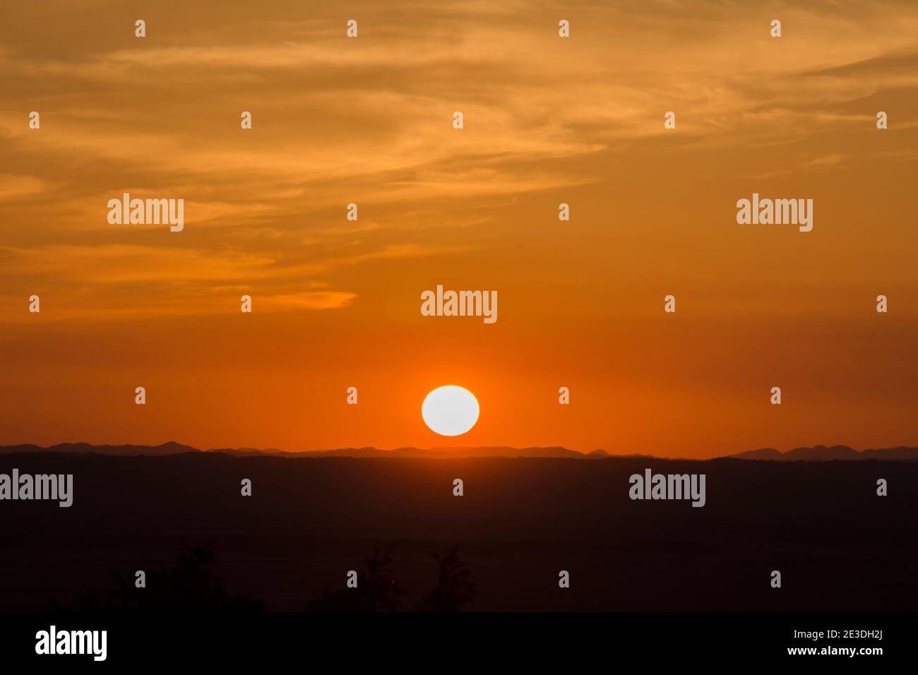 Un paesaggio del cielo dorato, della terra silhouette e del sole che tramonta Foto Stock