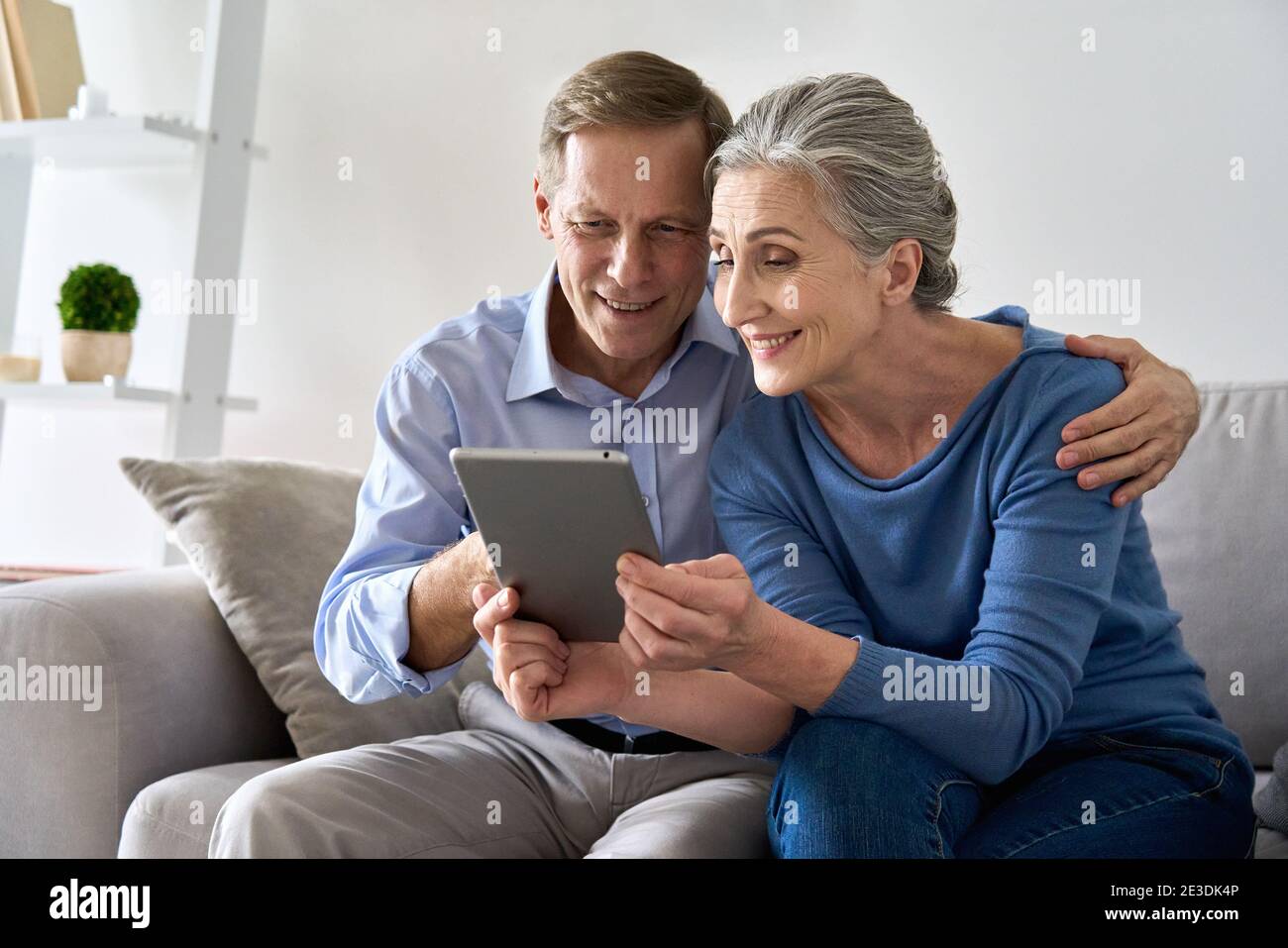 Felici i vecchi nonni senior che usano un tablet digitale seduto sul divano a casa. Foto Stock