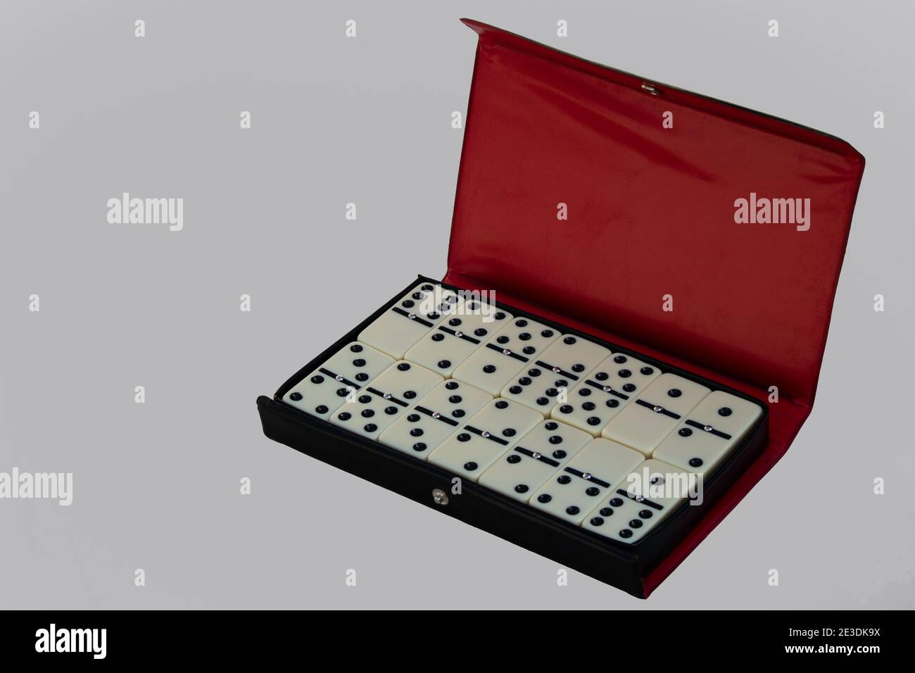 Set Domino disposto in un caso aperto isolato su sfondo bianco con spazio vuoto per il testo. Custodia nera e rossa con dominoe Foto Stock