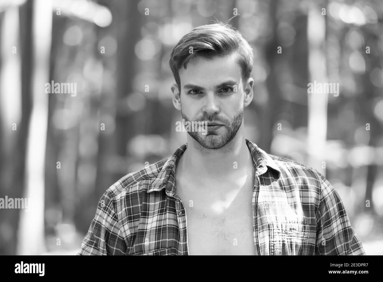 Giovane uomo con peli del viso non rasati in camicia aperta plaid paesaggio estivo naturale all'aperto, pelle. Foto Stock