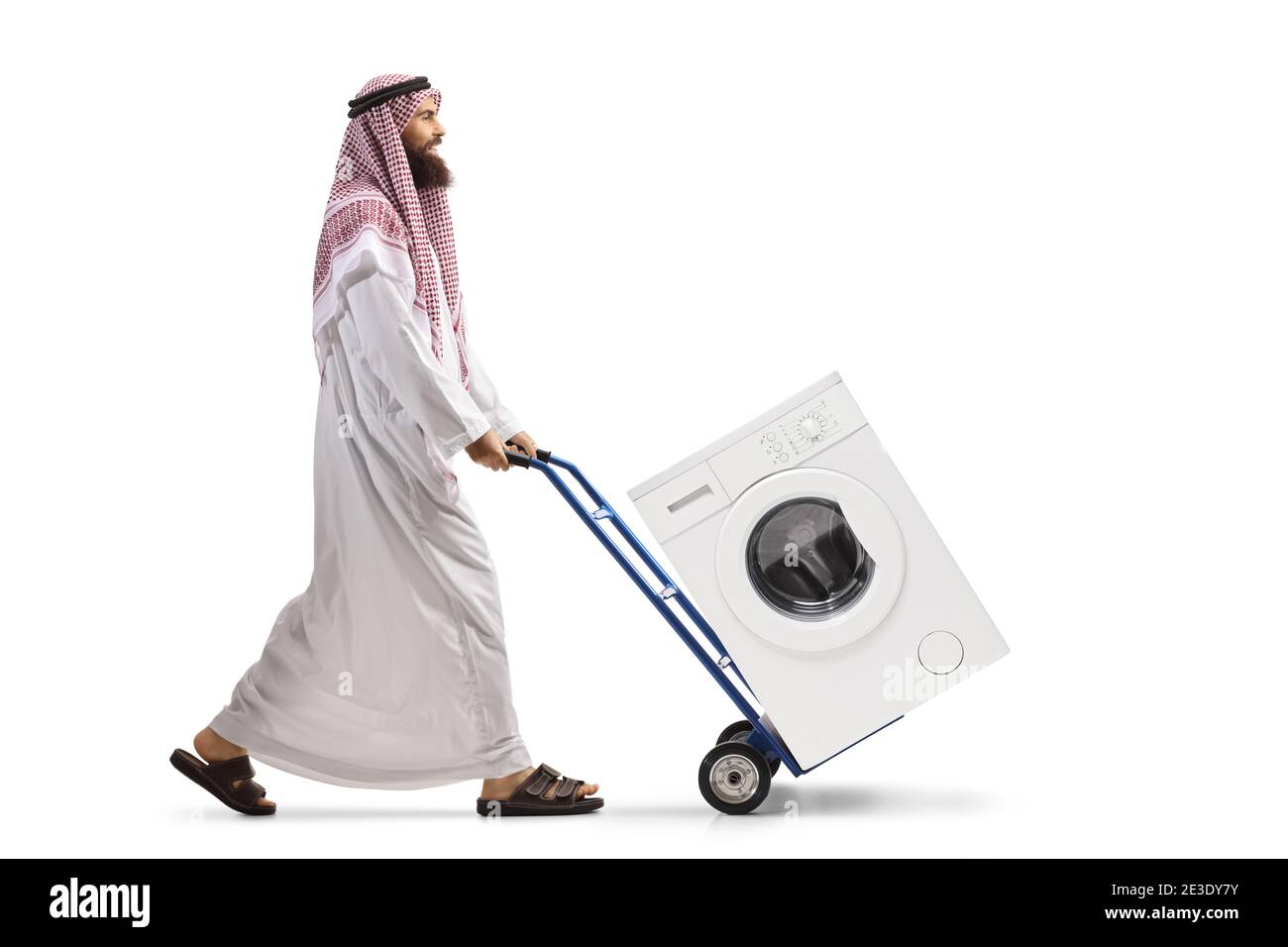 Foto di profilo a lunghezza intera di un uomo arabo che spinge un carrello a mano con lavatrice isolato su fondo bianco Foto Stock