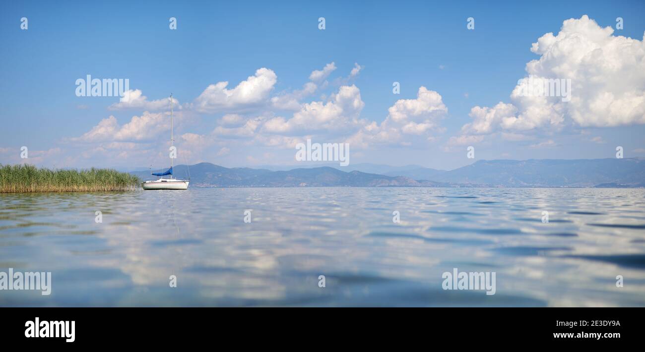 Vista laterale sul lago di una barca e riflessione nuvola Foto Stock