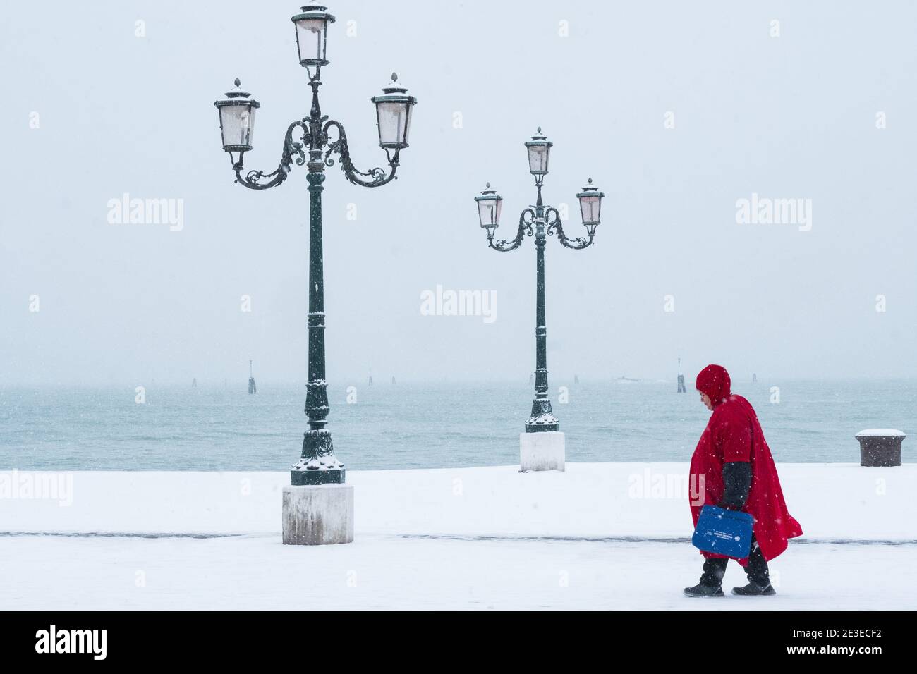 Venezia - Riva dei sette Martiri. Donna in mantello rosso cammina sotto la neve. Venezia - Donna cammina sotto la tempesta di neve sulla Riva dei sette Marti Foto Stock