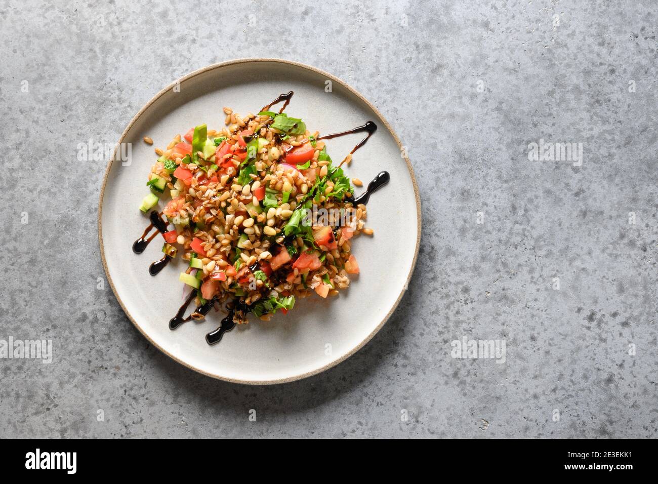 Insalata di farro di cereali interi con verdure su tavola grigia. Vista dall'alto. Spazio per il testo Foto Stock