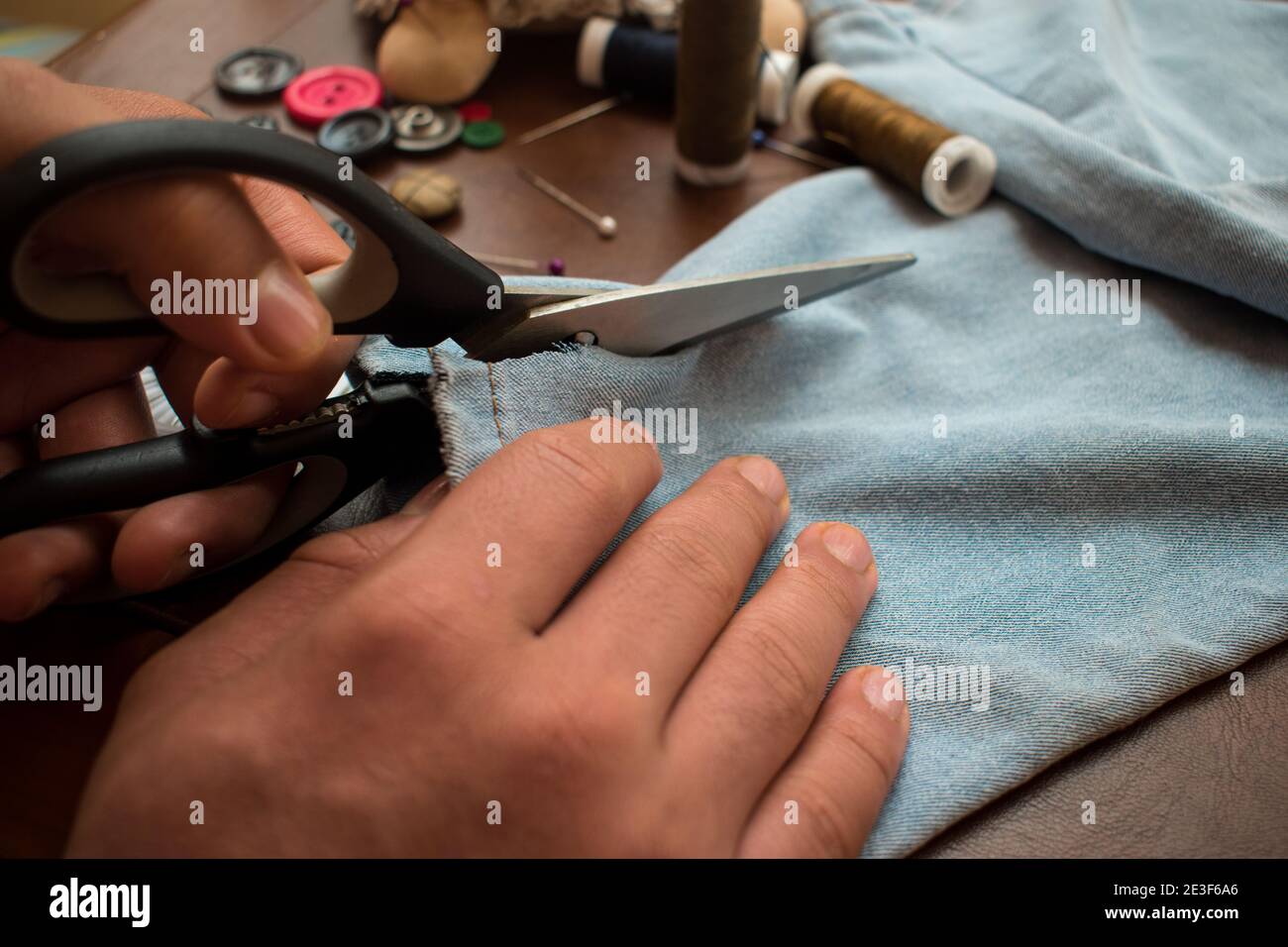 Su misura usando alcune forbici che tagliano alcuni pantaloni su un tavolo Foto Stock