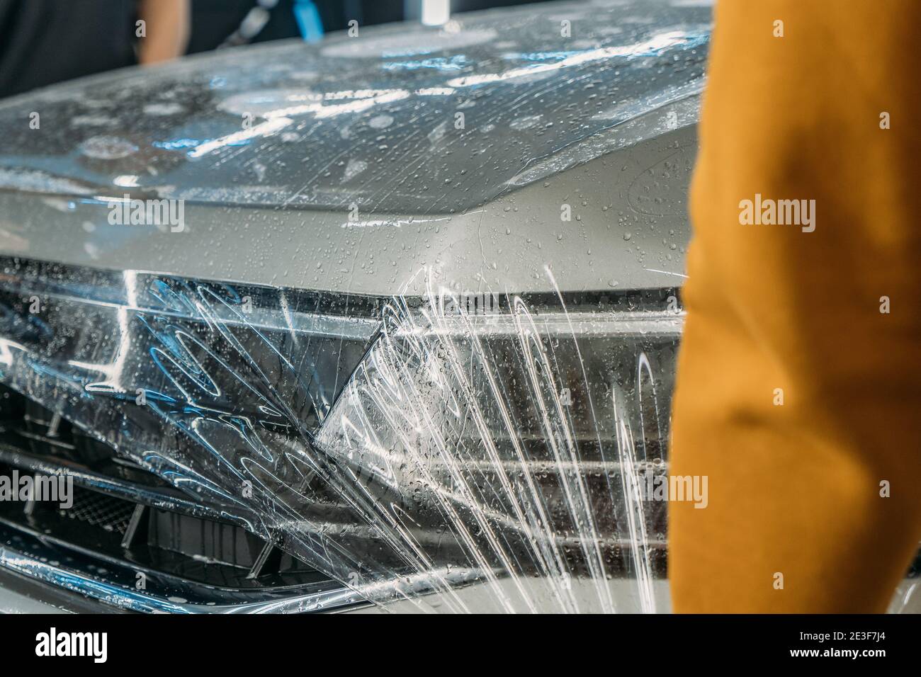 Pellicola di protezione trasparente per vernice o rivestimento anti-ghiaia avvolto sul cofano dell'auto. Dettagli auto. Foto Stock