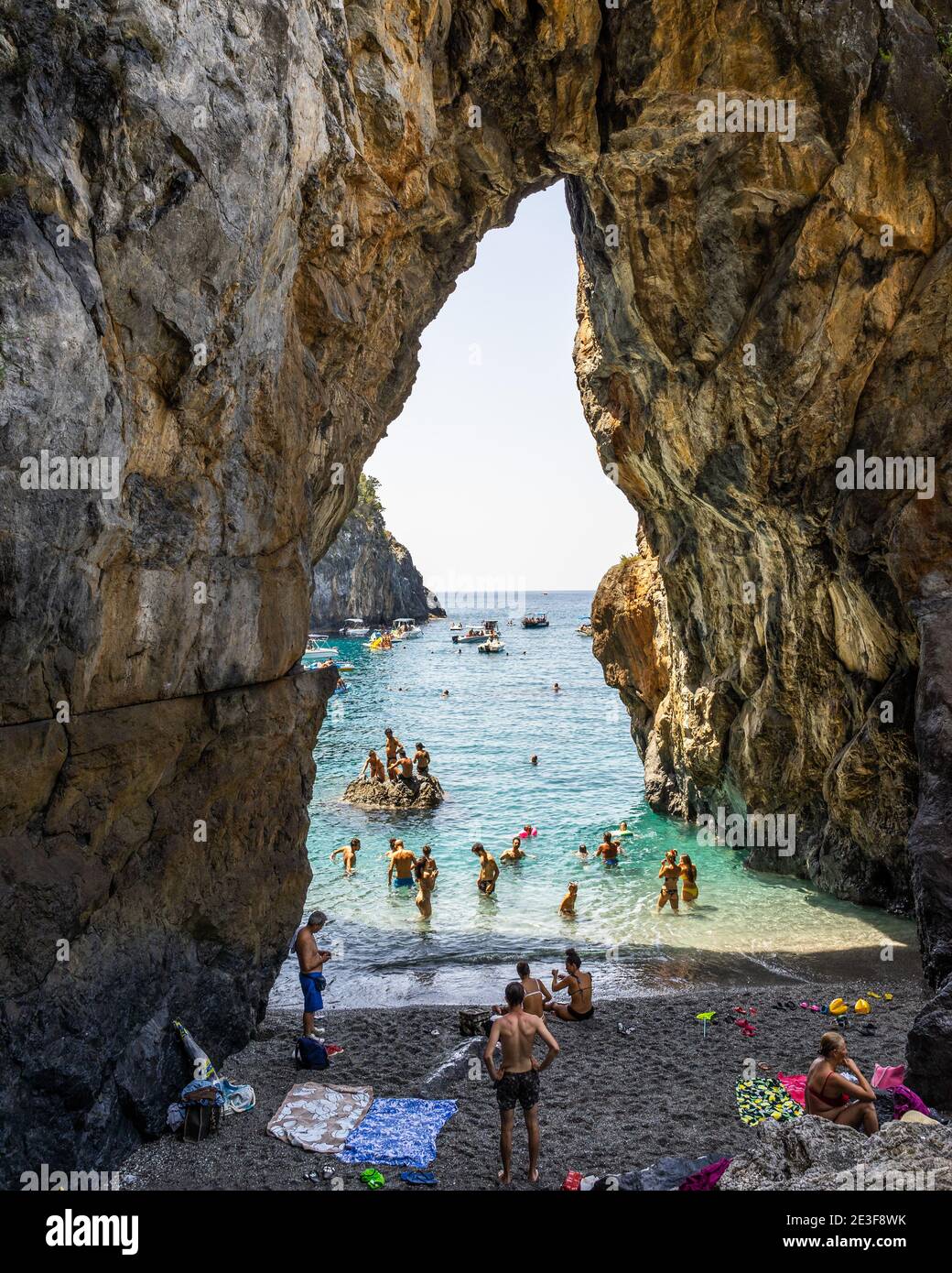San Nicola Arcella, Calabria – Agosto 2020: Nuotatori che si godono la spiaggia sotto l'arco naturale dell'Arcomagno Foto Stock