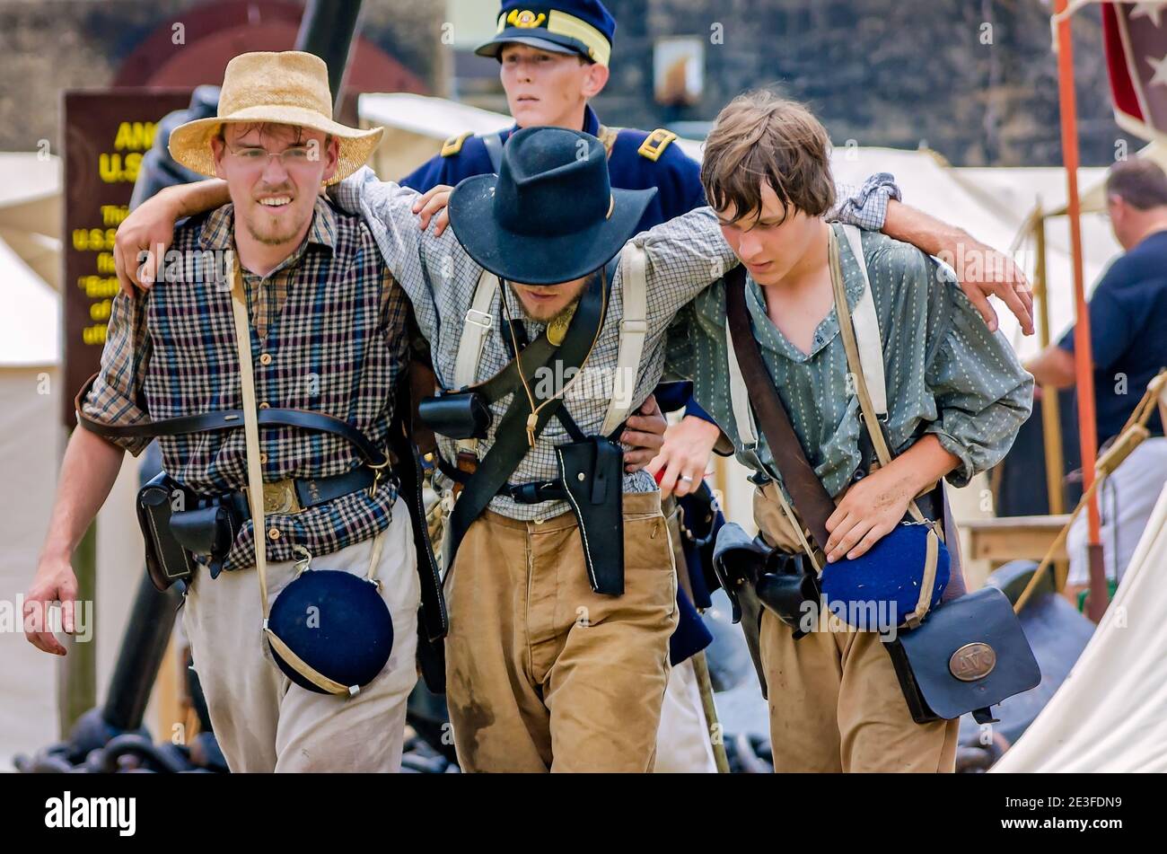 I reattori della guerra civile che rappresentano l'esercito confederato aiutano un soldato ferito a Fort Gaines durante un reenactment della 150a Battaglia di Mobile Bay. Foto Stock