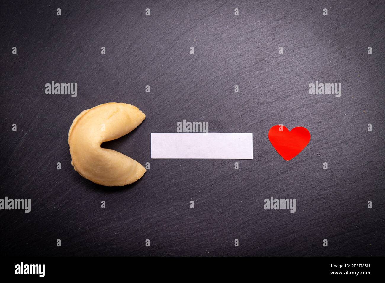 Cookie Fortune su sfondo nero con un cuore rosso per condividere i tuoi desideri di San Valentino. Un piccolo pezzo di carta vuoto per scrivere il vostro aforism circa l'amore. Foto Stock