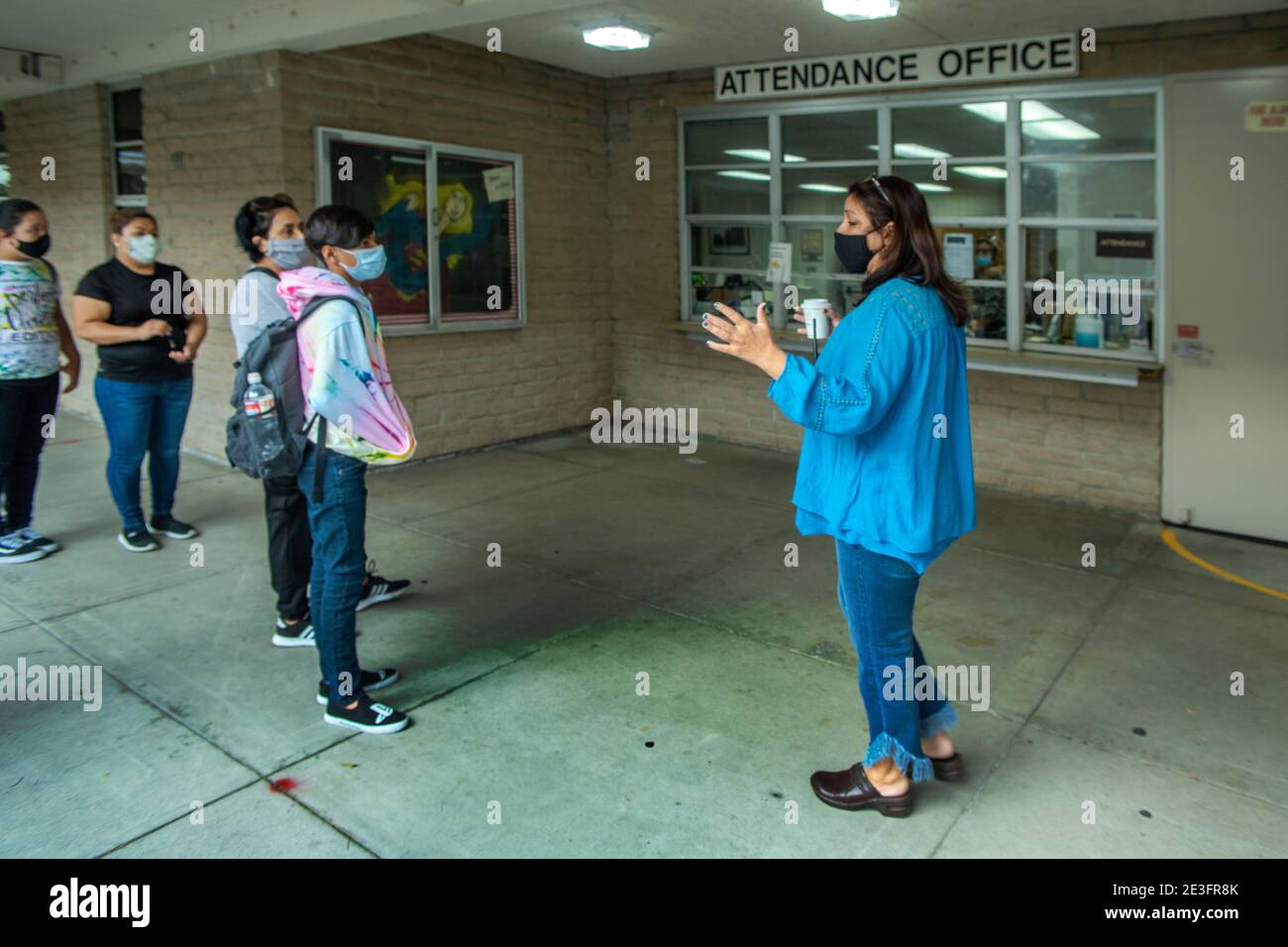 Indossando maschere di sicurezza a causa della pandemia del coronavirus, gli studenti ispanici in arrivo il primo giorno della scuola media in California sono accolti da t Foto Stock