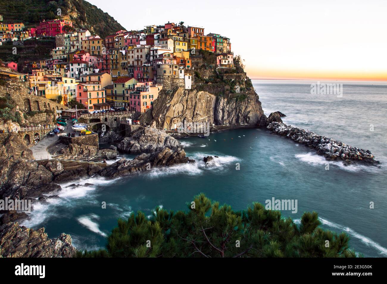 Vista panoramica a lunga esposizione del villaggio di Manarola contro le scogliere e il mare nel Parco Nazionale delle cinque Terre durante il tramonto, Liguria, la Spezia, Italia Foto Stock