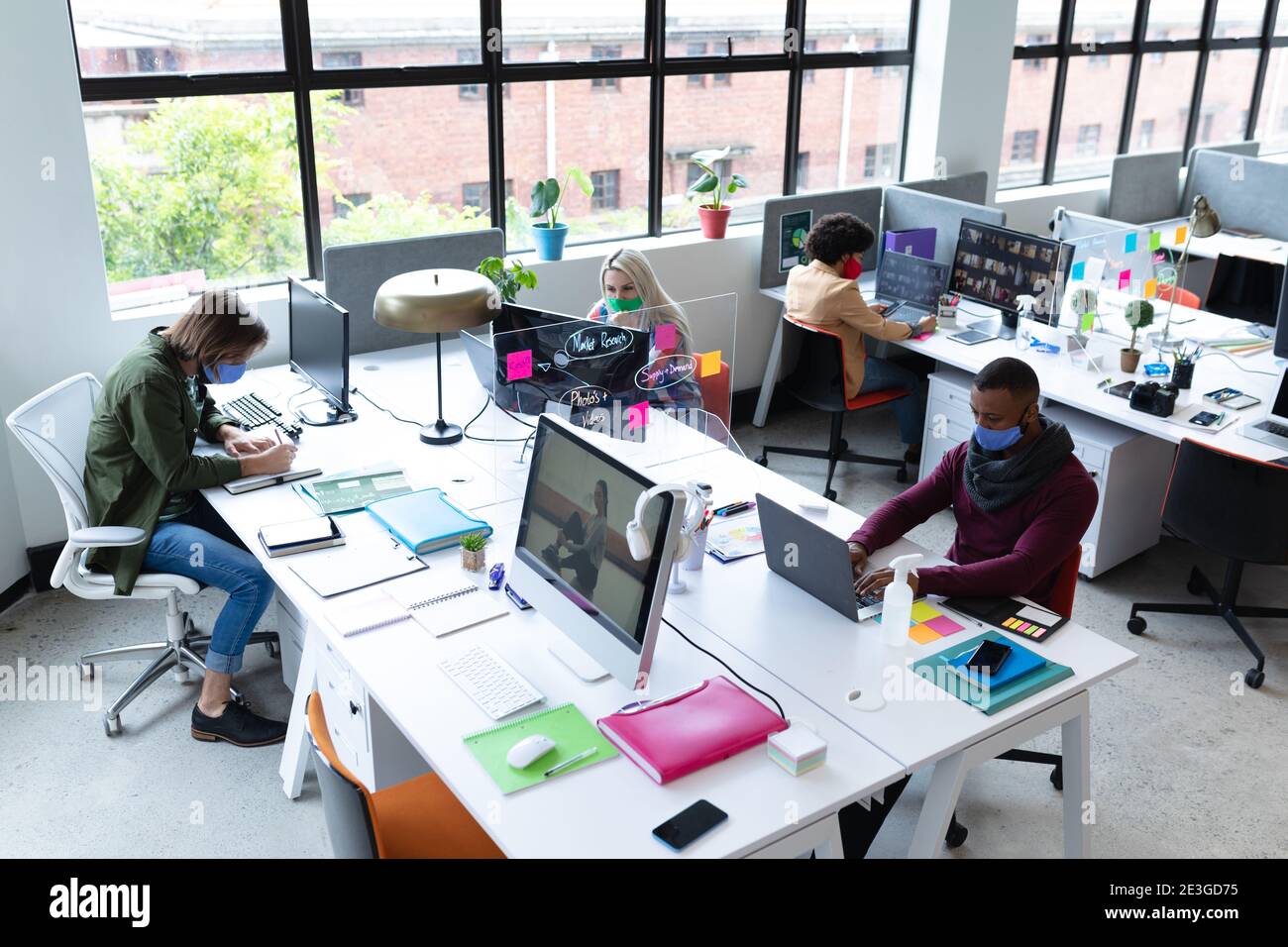 Gruppo vario di gente di affari che indossa le maschere del viso in creativo ufficio Foto Stock