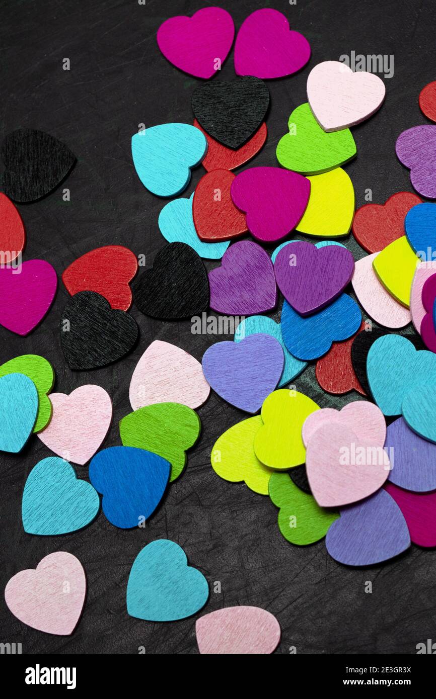 Un mucchio di piccoli cuori colorati su sfondo nero. Vista dall'alto Foto Stock